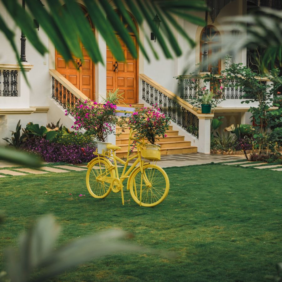 Picture-perfect yellow bicycle in the lawn at Heritage Village Resorts &amp; Spa, Goa, adding charm to the landscape.