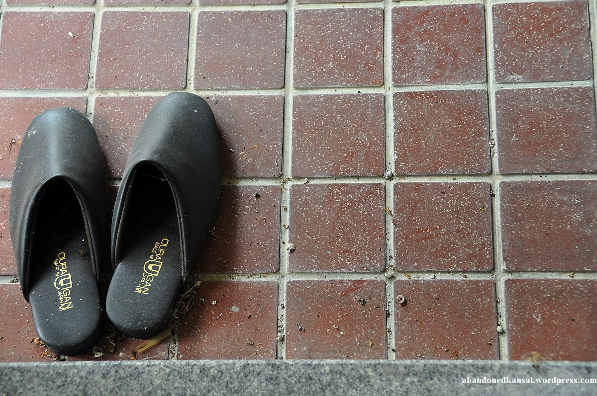 Entrance area with neatly lined up slippers at an abandoned Japanese spa, suggesting order and tranquility.