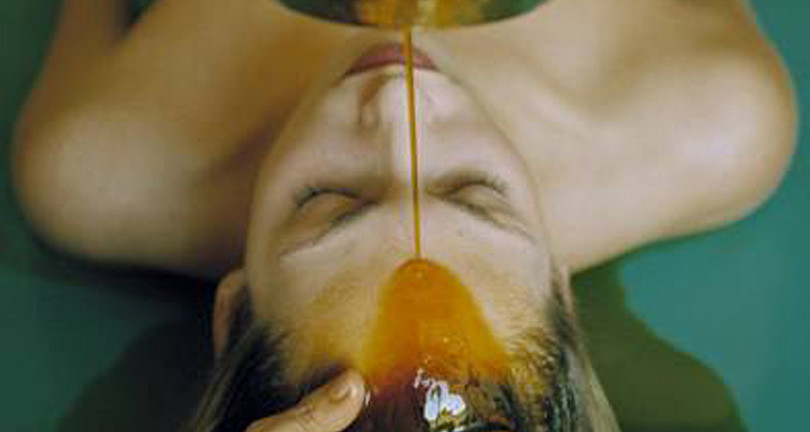 Woman receiving a head massage with oil poured over her forehead