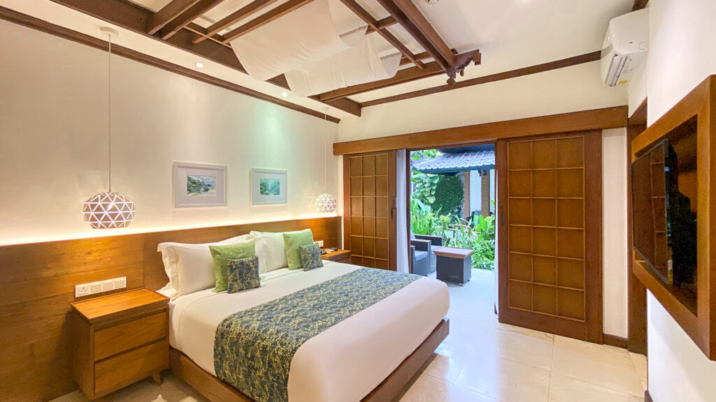 Balinese style deluxe garden room at Candi Beach Resort and Spa with balcony overlooking lush greenery.