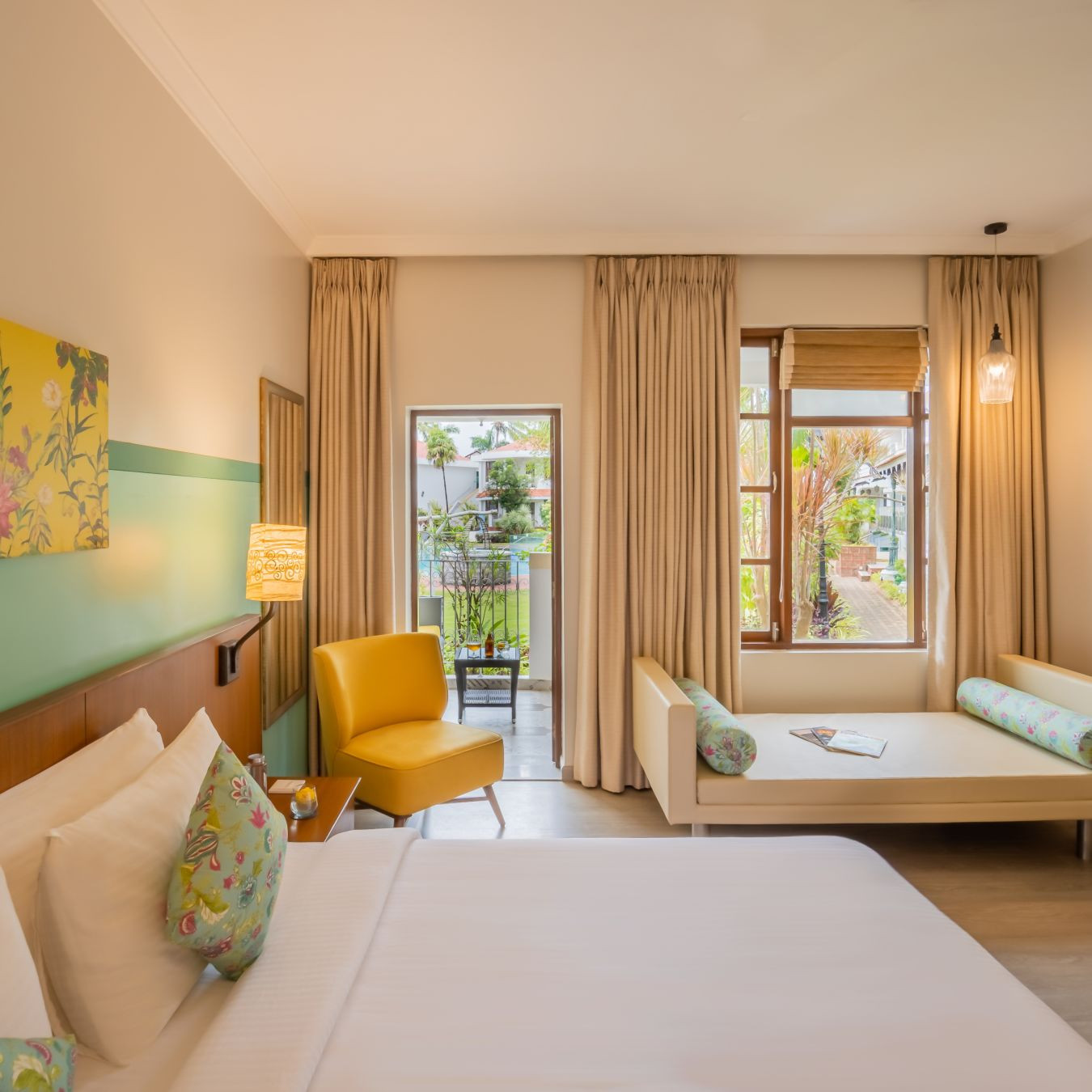 Deluxe Room with king bed and vibrant yellow decor at Heritage Village Resorts &amp; Spa, a premier Goa resort and spa.