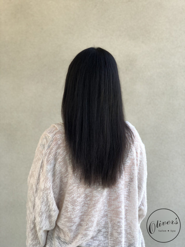 Alt: Back view of a woman with smooth, straight, shoulder-length black hair after a keratin treatment.