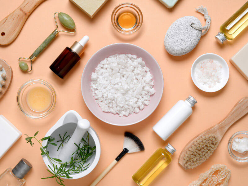 Essential spa and beauty tools for your own spa business, including skincare products, brushes, and applicators, set against a vibrant orange backdrop.