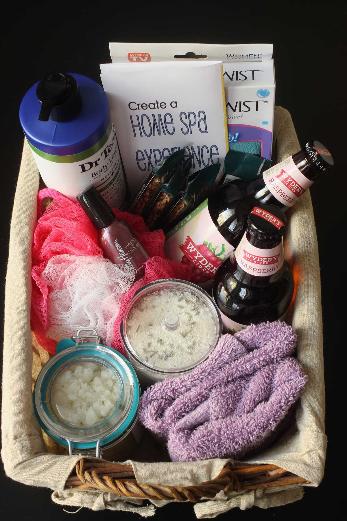 Spa gift basket filled with bath and body products, snacks, and a drink.