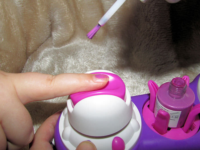 alt: Close up of a child's finger positioned in the Easy Nails Nail Spa, ready for polishing.