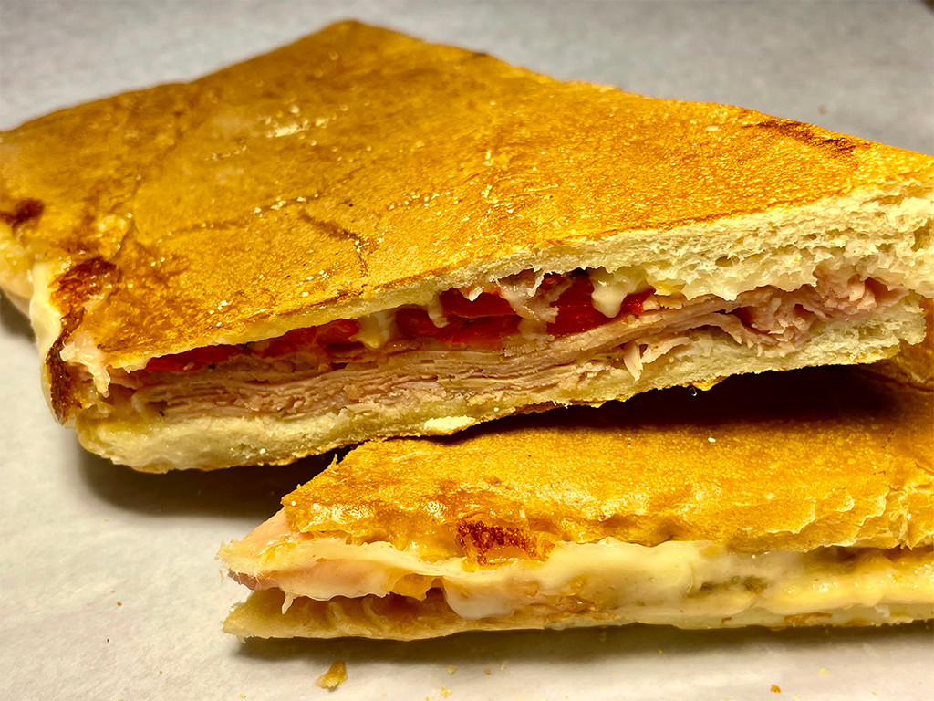 Montrose Spa's Missing Link pressed sandwich featuring rosemary, sun-dried tomato, ham, provolone cheese, and sweet roasted red peppers