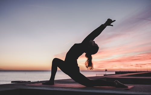A person practicing yoga outdoors with a scenic mountain backdrop