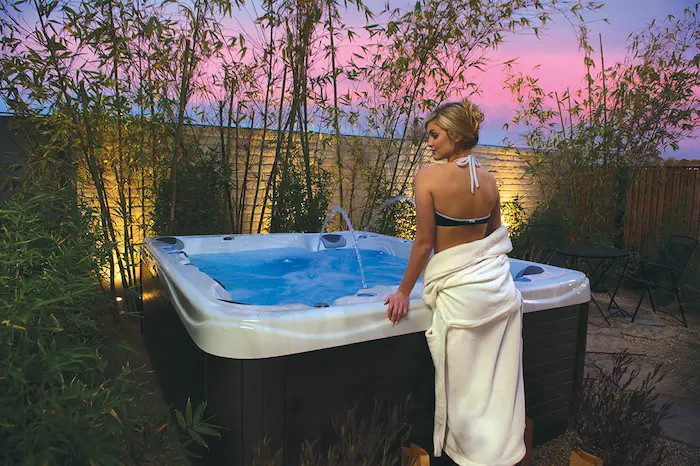 Woman standing near a hot tub after getting JR Spa & hot tub services.