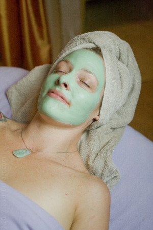 Woman enjoying a facial treatment at a spa, emphasizing relaxation and skincare benefits.